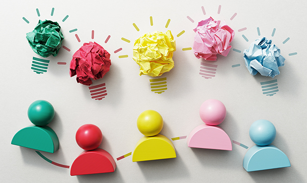 wooden block figures of different colors with lightbulbs above their heads